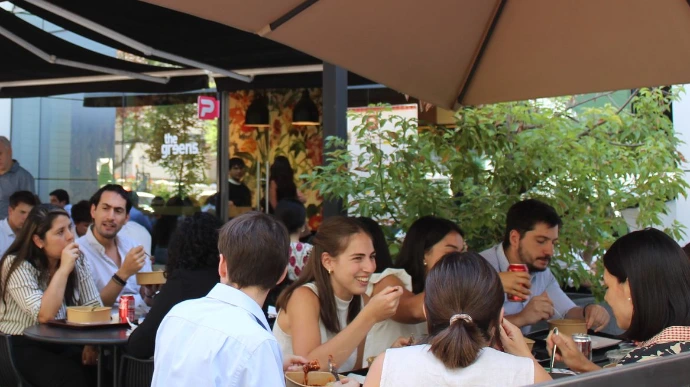 Clientes disfrutando almuerzo saludable en terraza con platos de The Greens en Las Condes, Santiago
