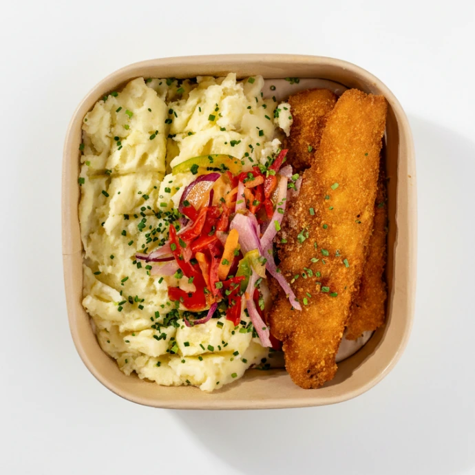 Bowl de puré con merluza, adornado con vegetales salteados. Contenedor de cartón listo para llevar